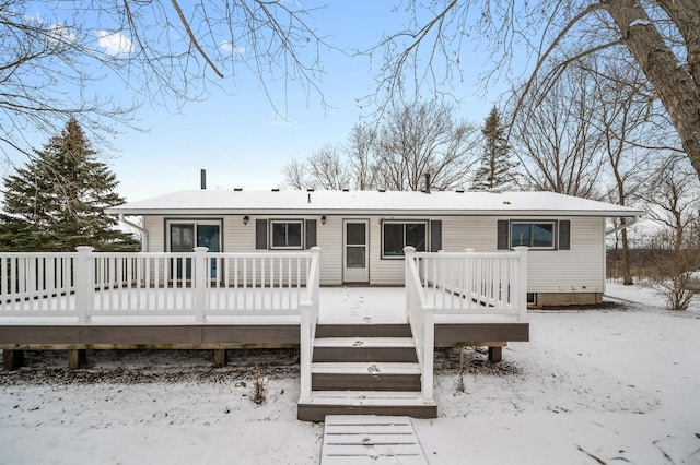 snow covered back of property with a deck