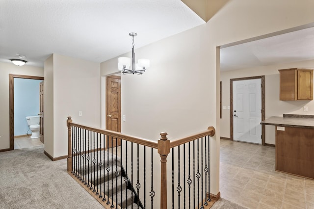 hallway with light carpet and a chandelier