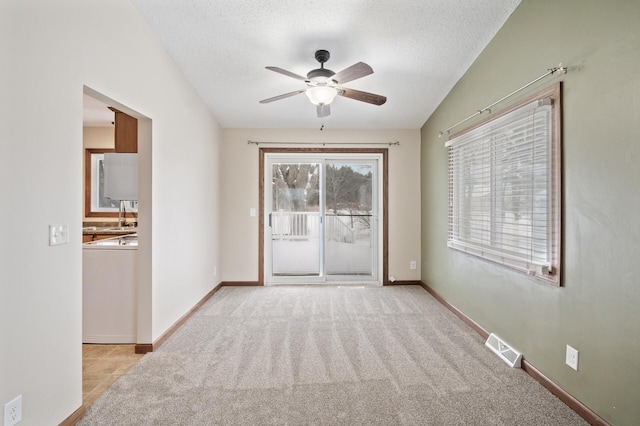 carpeted spare room with ceiling fan, washer / dryer, a textured ceiling, and vaulted ceiling