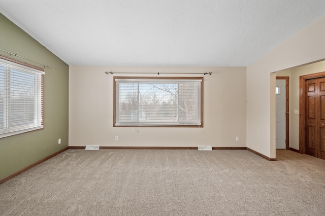 unfurnished room with light carpet, vaulted ceiling, and plenty of natural light