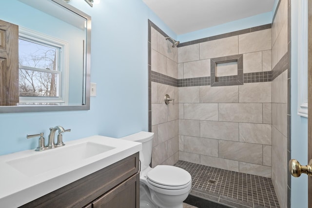 bathroom featuring tiled shower, vanity, and toilet