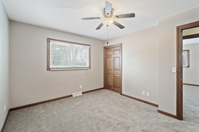 unfurnished bedroom featuring ceiling fan, a closet, and light colored carpet