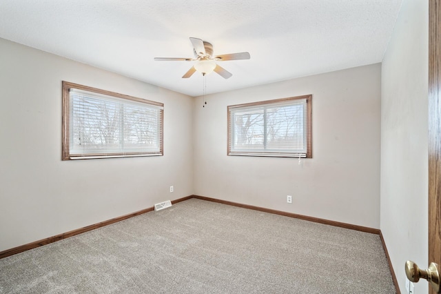 carpeted spare room with a wealth of natural light and ceiling fan