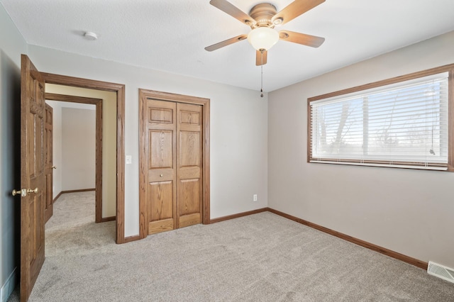 unfurnished bedroom featuring a closet, light colored carpet, and ceiling fan