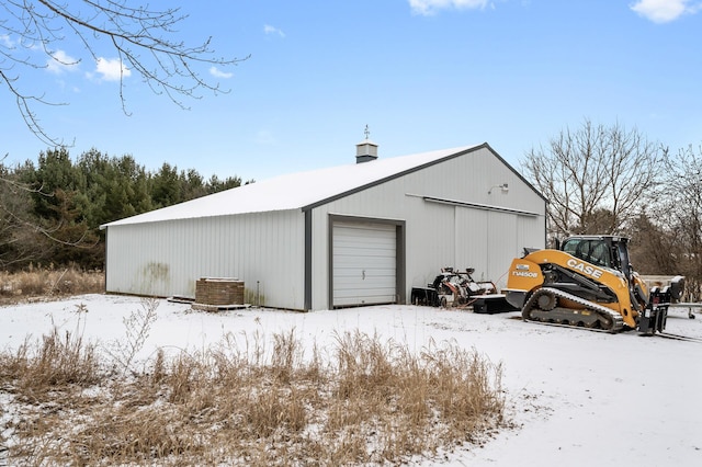 snow covered structure featuring a garage