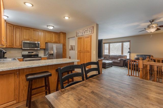 kitchen with tasteful backsplash, a breakfast bar, kitchen peninsula, sink, and stainless steel appliances