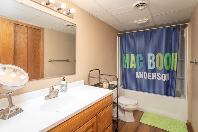 full bathroom with toilet, vanity, a drop ceiling, shower / tub combo, and wood-type flooring