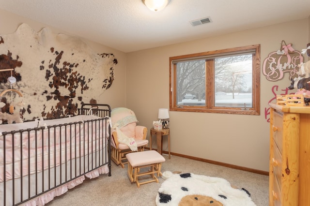 carpeted bedroom with a textured ceiling and a crib