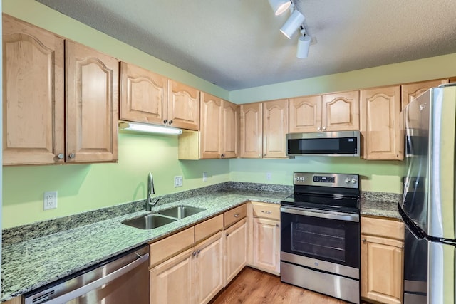 kitchen with sink, track lighting, light brown cabinetry, and appliances with stainless steel finishes