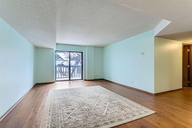 empty room with a textured ceiling and light hardwood / wood-style flooring