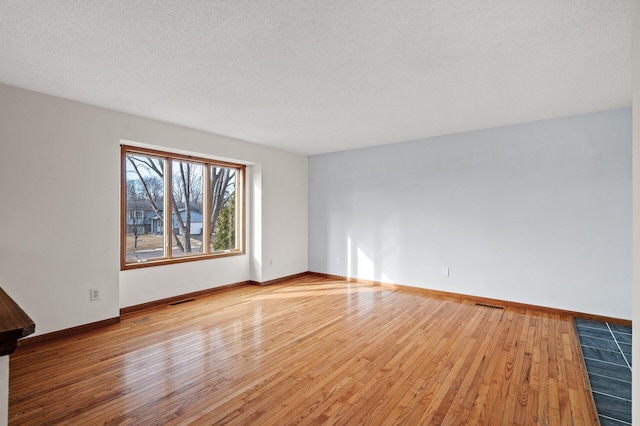 spare room with light hardwood / wood-style floors and a textured ceiling