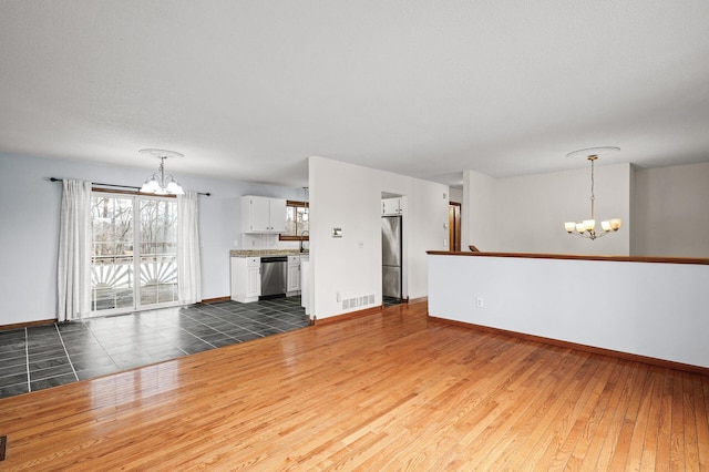 unfurnished living room featuring dark wood-type flooring, sink, and an inviting chandelier