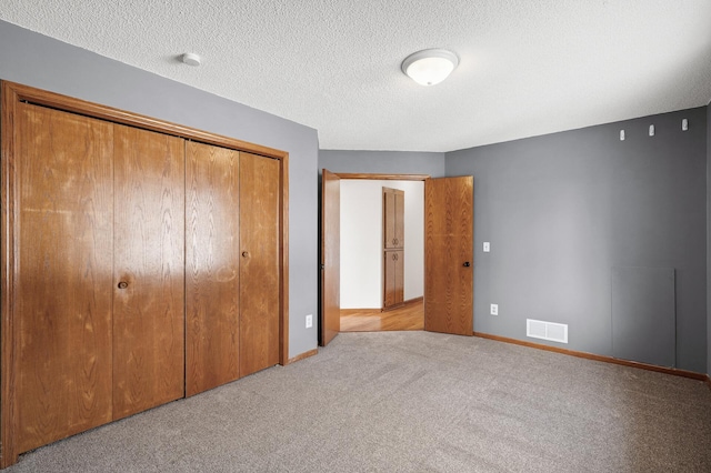 unfurnished bedroom featuring light colored carpet, a closet, and a textured ceiling