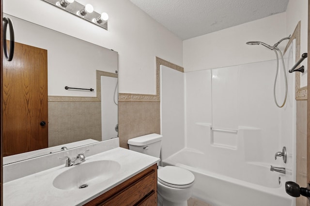 full bathroom with toilet, bathing tub / shower combination, a textured ceiling, tile walls, and vanity