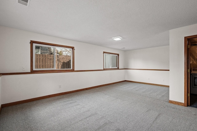 carpeted spare room with washer / clothes dryer and a textured ceiling