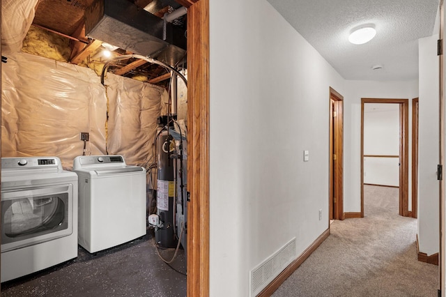 washroom featuring water heater, washer and clothes dryer, and a textured ceiling