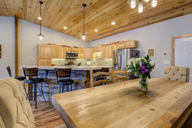 dining area featuring vaulted ceiling, light hardwood / wood-style flooring, and wooden ceiling