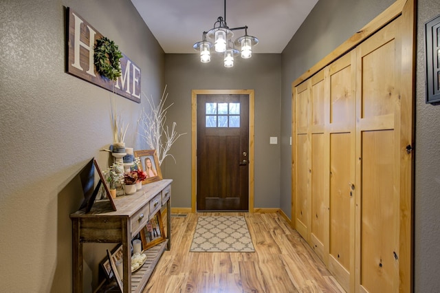 foyer entrance featuring light hardwood / wood-style floors and a notable chandelier