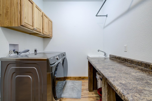 washroom with cabinets, independent washer and dryer, sink, and light wood-type flooring