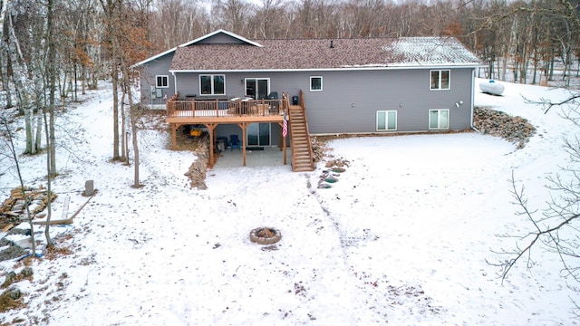 snow covered back of property with an outdoor fire pit and a wooden deck