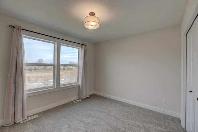 unfurnished room with light colored carpet and a textured ceiling