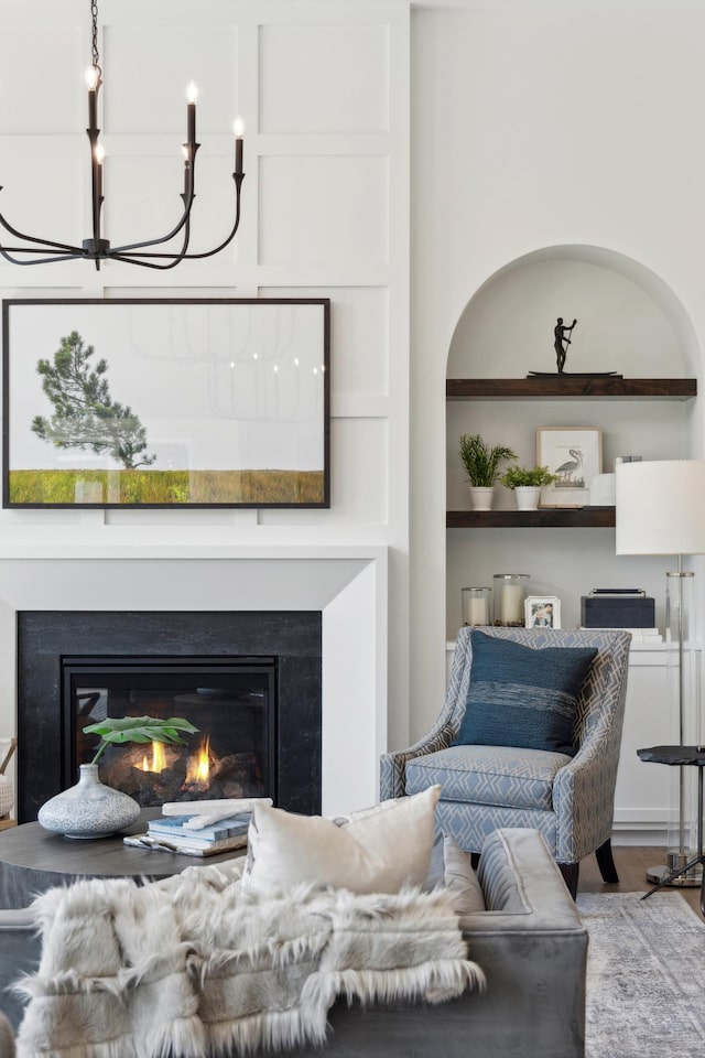 living room featuring built in features, a chandelier, and light hardwood / wood-style flooring