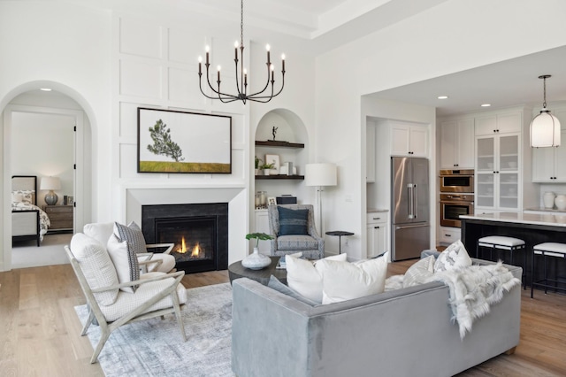 living room with a chandelier, light wood-type flooring, and built in features