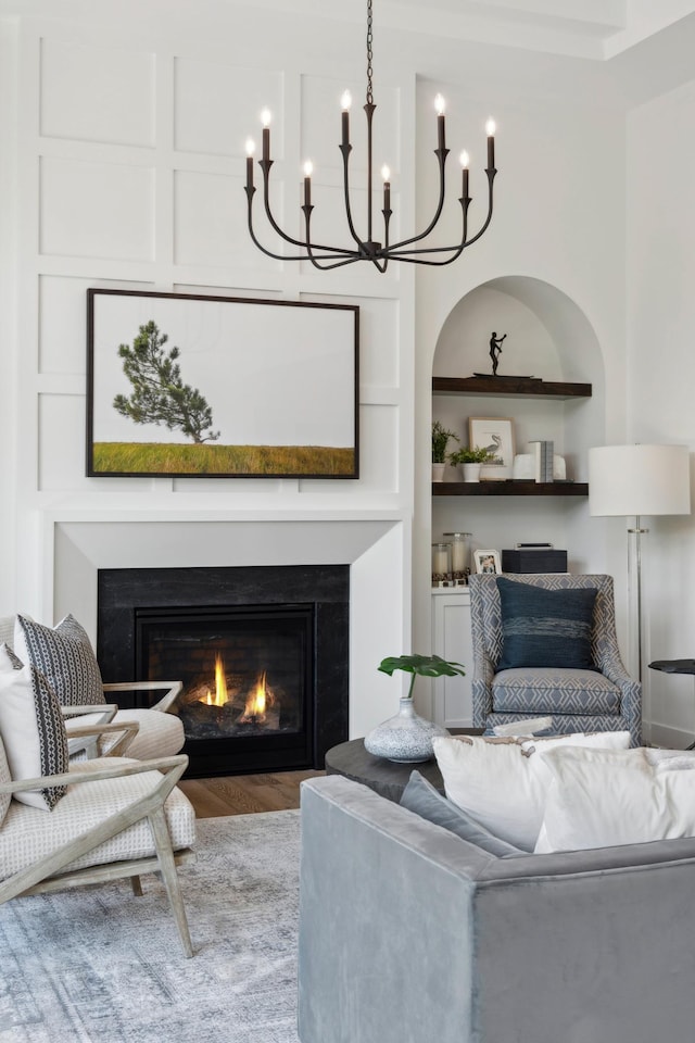 living room featuring built in shelves, wood-type flooring, and a notable chandelier