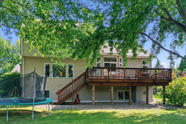 back of house with a deck, a trampoline, a yard, and stairs