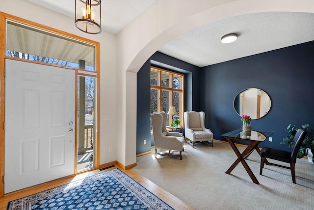 foyer entrance with baseboards, arched walkways, and plenty of natural light