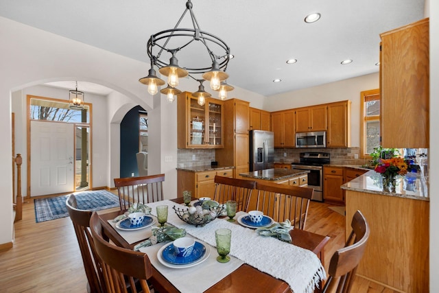 dining area featuring an inviting chandelier, recessed lighting, light wood-style floors, and arched walkways