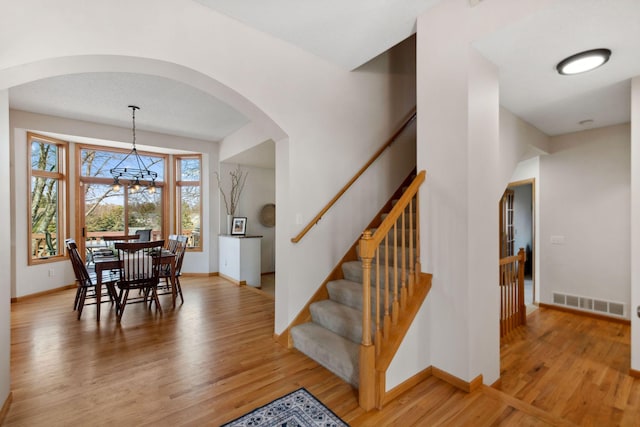 dining room featuring visible vents, baseboards, light wood-style flooring, arched walkways, and stairs