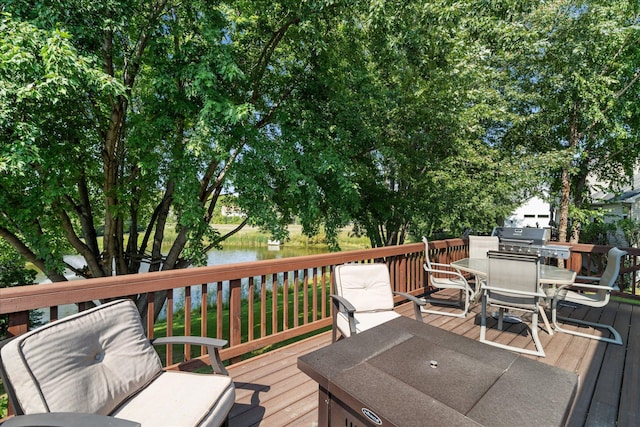 wooden terrace with a water view and outdoor dining space