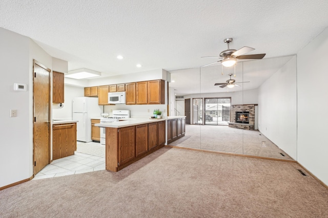 kitchen with a stone fireplace, white appliances, light carpet, a textured ceiling, and ceiling fan