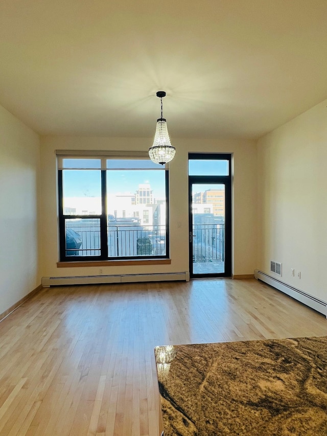 unfurnished dining area featuring a baseboard heating unit, light hardwood / wood-style flooring, and a notable chandelier