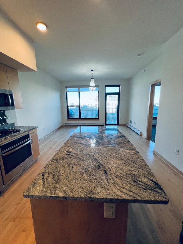 kitchen featuring pendant lighting, light hardwood / wood-style flooring, dark stone counters, and appliances with stainless steel finishes