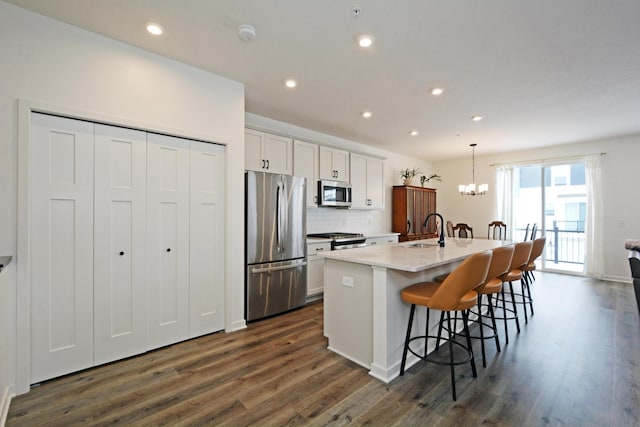 kitchen featuring white cabinets, appliances with stainless steel finishes, a kitchen breakfast bar, sink, and a center island with sink