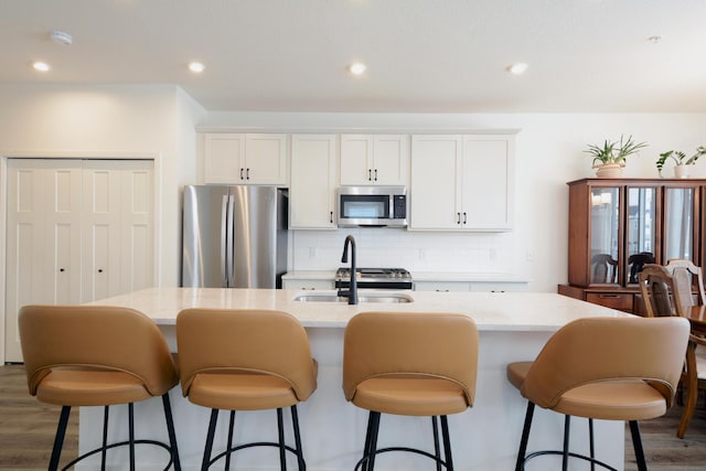 kitchen with appliances with stainless steel finishes, white cabinetry, and an island with sink