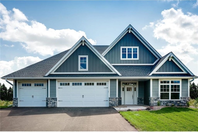 craftsman inspired home featuring a garage and a front lawn