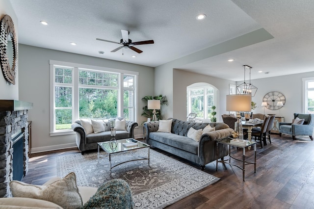 living room featuring a textured ceiling, dark hardwood / wood-style flooring, a healthy amount of sunlight, and a fireplace