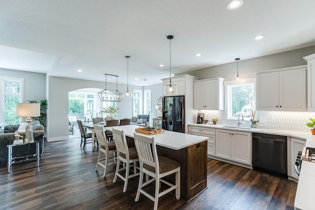 kitchen with white cabinetry, a center island, hanging light fixtures, and black appliances