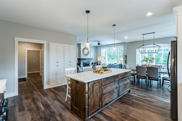 kitchen featuring black refrigerator, ceiling fan, dark wood-type flooring, hanging light fixtures, and a center island