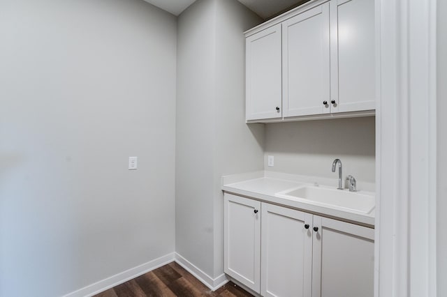 clothes washing area with dark wood-type flooring and sink