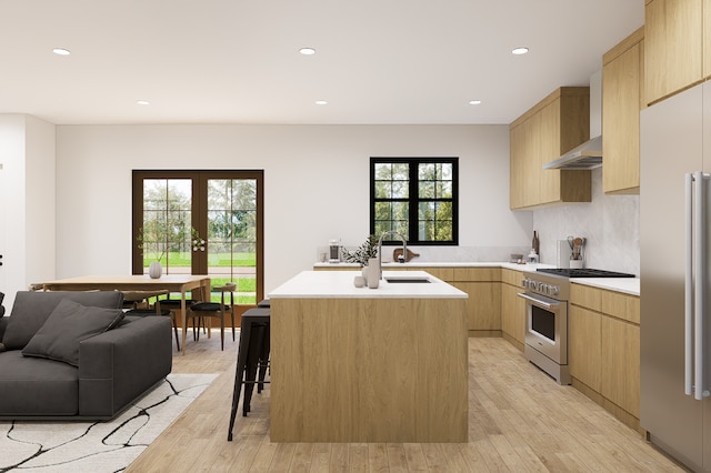 kitchen with light wood-type flooring, high end appliances, sink, light brown cabinets, and a center island