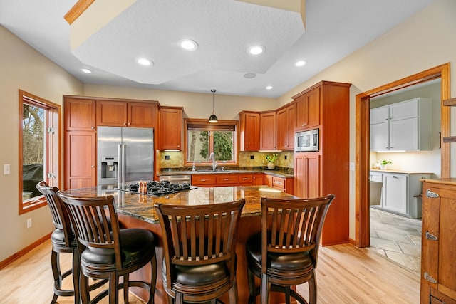 4167 Hallgren Ln, Excelsior, MN 55331 - kitchen featuring appliances with stainless steel finishes, a sink, backsplash, dark stone counters, and a breakfast bar area