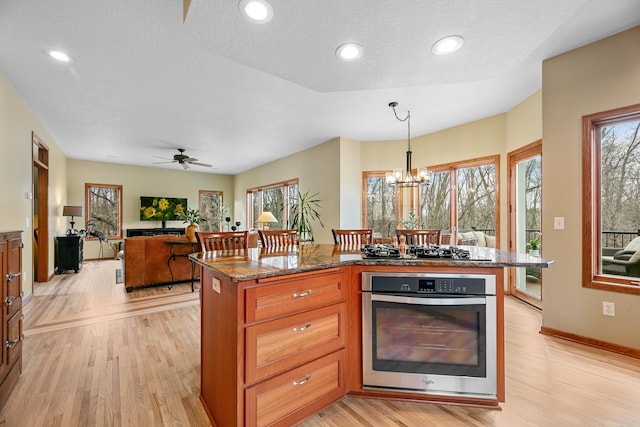 4167 Hallgren Ln, Excelsior, MN 55331 - kitchen featuring oven, light wood finished floors, gas cooktop, dark stone countertops, and decorative light fixtures