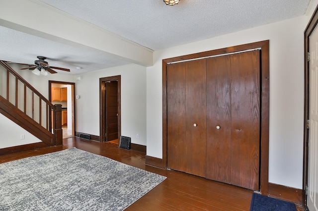 foyer featuring baseboards, visible vents, stairway, wood finished floors, and a textured ceiling