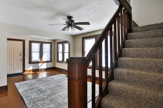 foyer featuring baseboards, ceiling fan, dark wood-type flooring, stairs, and a textured ceiling