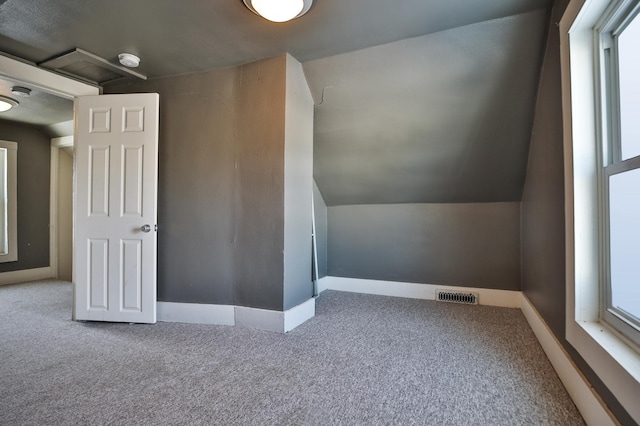 additional living space with lofted ceiling, baseboards, visible vents, and carpet flooring