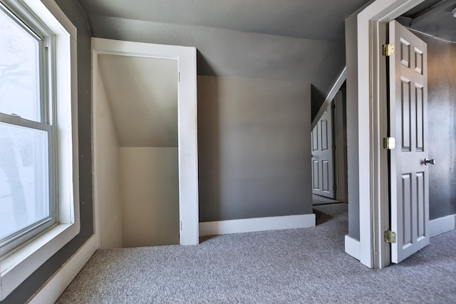 additional living space with carpet floors, lofted ceiling, a healthy amount of sunlight, and baseboards